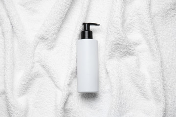 Bottle of shampoo on white towel - obrazy, fototapety, plakaty