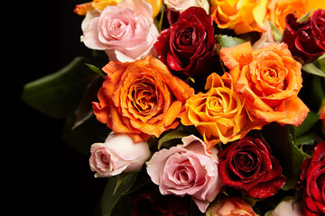 Bouquet of different color roses with water drops on petals on a black background. Red, orange and pink flowers. Romantic Valentine's Day Gift
