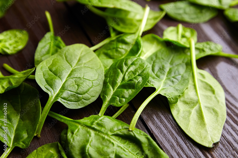 Wall mural Spinach fresh green leaves in a wooden background