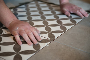 Tiler laying the ceramic tile on the floor. Professional worker makes renovation. Construction. Hands of the tiler. Home renovation and building new house