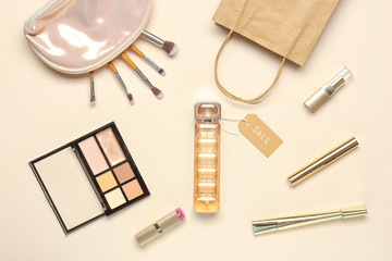 Bottle of perfume with makeup cosmetics and bag on light background