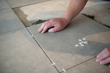 Tiler laying the ceramic tile on the floor. Professional worker makes renovation. Construction. Hands of the tiler. Home renovation and building new house