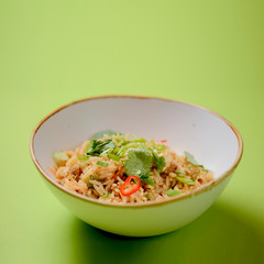 Japanese food rice served with vegetables in a white bowl over bright green background. Japanese cuisine isolated.