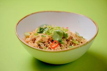 Japanese food rice served with vegetables in a white bowl over bright green background. Japanese cuisine isolated.