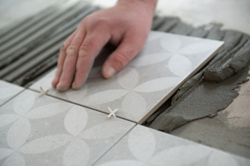 Tiler laying the ceramic tile on the floor. Professional worker makes renovation. Construction....