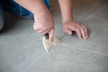 Tiler laying the ceramic tile on the floor. Professional worker makes renovation. Construction. Hands of the tiler. Home renovation and building new house