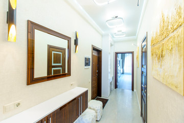 a long corridor in the apartment with beige Wallpaper, numerous doors and light yellow abstract...