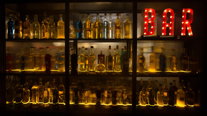 BAR sign with lights in the dark. with bottles of alcohol.  