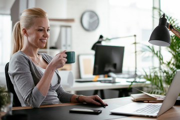 Young successful businesswoman working in office while drinking coffee. Beautiful woman at work.