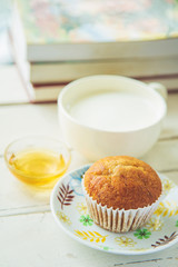Close up banana cake on white plate with honey and cup of milk and books background.