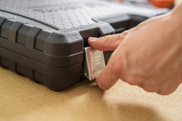 Male hand opening the case with tools for repair of something. Do it yourself