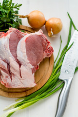 Raw pork chops, parsley, chives and onions. On a cutting board. Ready for cooking