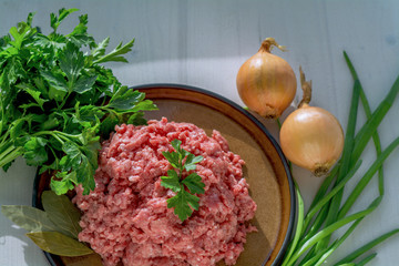 Minced meat on a plate with parsley, laurel fox, green and onions