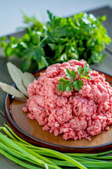 Minced meat on a plate with parsley, laurel fox, green and onions  A