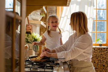 horizontal photo of the process of making pancakes by mom and daughter