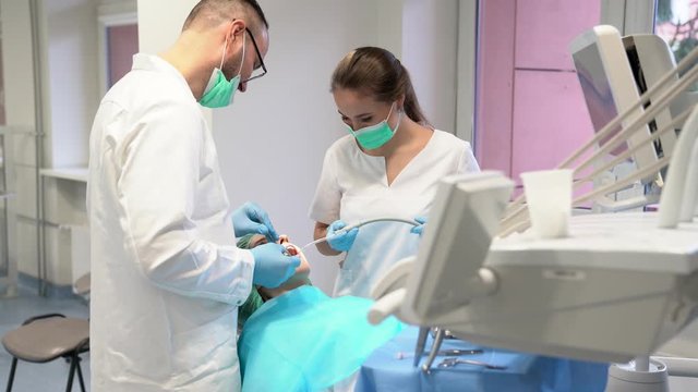 Dentist and his assistant examining the teeth of a patient