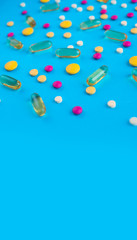 Spilled colored medications and pills on a blue background. Pharmacology and medicine struggle for health.