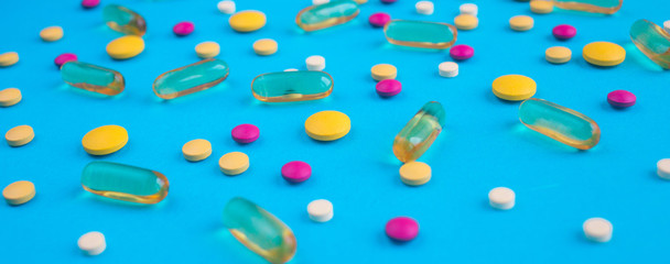 Spilled colored medications and pills on a blue background. Pharmacology and medicine struggle for health.