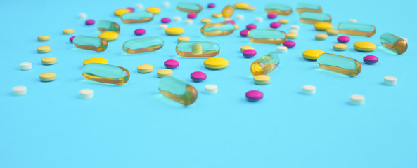 Spilled colored medications and pills on a blue background. Pharmacology and medicine struggle for health.