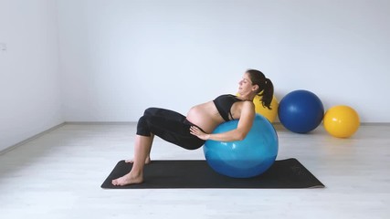 Slow motion shot of pregnant woman laying on exercise ball - Powered by Adobe