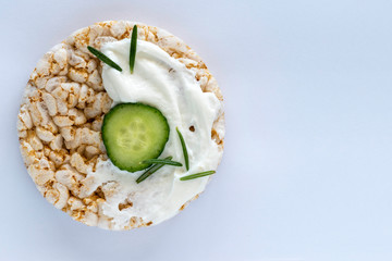 Crisp bread sandwich with cream cheese, cucumber slice and fresh rosemary on soft blue background with copy space. 