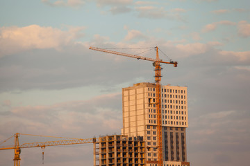 construction site with cranes against the background of bright evening clouds	