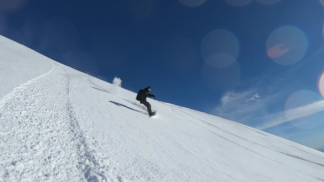 Man riding freeride on snowboard on fluffy powder snow in winter mountain. Snowboarder with avalanche airbag bagpack ride fast on snowy mountain resort on sea landscape. Winter people activity.