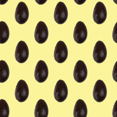 Seamless pattern of whole avocado isolated on a light yellow. Food background. Flat lay