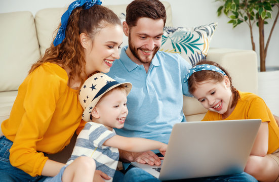 Cheerful family surfing laptop together near couch