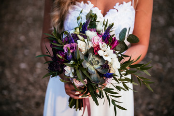 Beautiful bride is holding a wedding colorful bouquet. Beauty of colored flowers. 