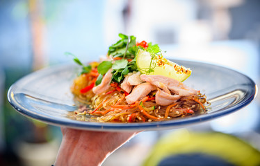 Waiters hand holding a plate with food in cafe or restaurant