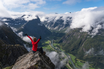 A woman hiker sitting on rock looking at mountain, Romsdalseggen trail, Norway, Scandinavia