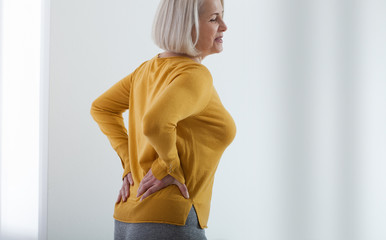 Middle aged woman with pain in the backache and lower back. Concept photo with indicating location...