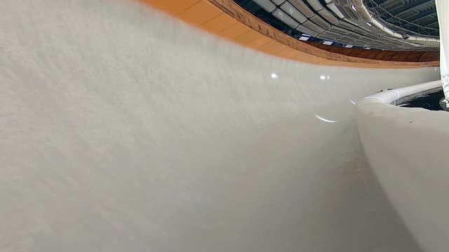 Athlete sliding on luge in ice centre. Rider in bodysuit and helmet riding sled inside slide. Winter sledging sport. Skeleton winter sports. Game ice sled, sportsman on slide track
