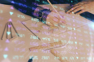 Double exposure of man's hands writing notes of stock market with forex chart.