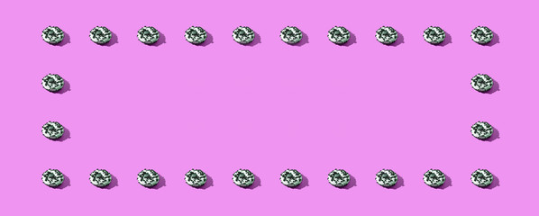 Many donuts horizontal frame. Set same cakes concept. Hard shadow. Top view colorful background. White, black, pink colors. Unhealthy food art. Circle bright dessert border