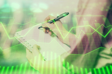 Multi exposure of hands making notes with forex chart huds. Stock market concept.