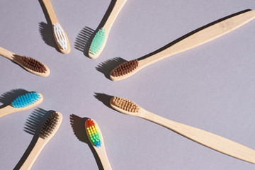 Many eco toothbrash at table. Different color bamboo tooth brush for morning hygiene routine. Diagonal photo up view. Flat lay soft shadow. Sun round concept