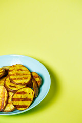 grilled potatoes until golden brown in a blue plate on a yellow background