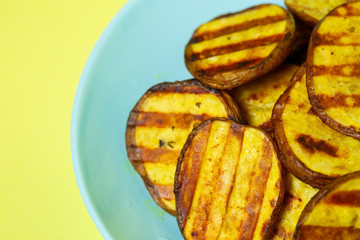 grilled potatoes until golden brown in a blue plate on a yellow background