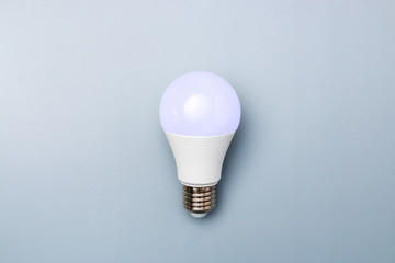 led bulb with purple light against a grey background with copy space. energy efficiency concept