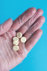 medical tablets close on the blue background. paramedic hand holds pill. Coronavirus, flu respiratory disease concept
