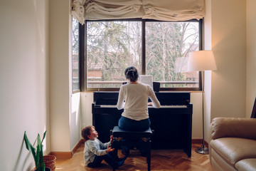 Mom trying to play the piano at home while attending to naughty children than wants to play. Family...