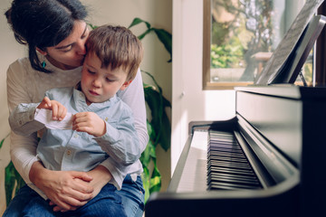 Mom teaching her son at home piano lessons. Family lifestyle spending time together indoors. Children with musical virtue and artistic curiosity. Educational musical activities for little kid.