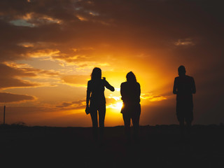 Fototapeta na wymiar Three friends walking to the sunset