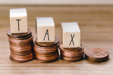 Wooden cubes with the word Tax on money climbing staits, pile of coins ,Tax Concept background