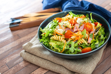 Salad with fusilli pasta accompanied tomatoes, mozzarella, smoked ham and italian cheese