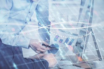 Double exposure of chart with businessman typing on computer in office on background. Concept of hard work.