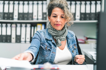 Mature woman delivering paperwork and full of files in the background