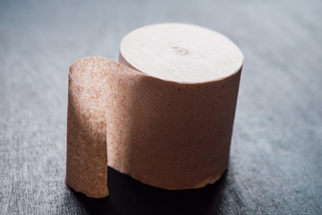 Rigid brown Soviet toilet paper) (one roll) on a dark background.